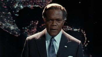 Movie still from “RoboCop” (2014), directed by José Padilha – A man in a suit and tie looking at the camera; Medium shot, Low angle