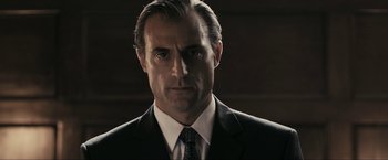 Movie still from “RocknRolla” (2008), directed by Guy Ritchie – A person wearing a suit and tie; Close Up shot, Low angle