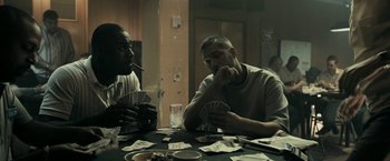 Movie still from “RocknRolla” (2008), directed by Guy Ritchie – Two men sitting at a table playing cards; Medium shot, Over the shoulder angle