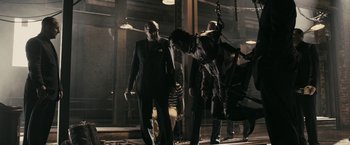 Movie still from “RocknRolla” (2008), directed by Guy Ritchie – A group of men standing next to each other on a street; Wide shot, Low angle