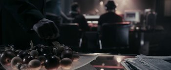 Movie still from “RocknRolla” (2008), directed by Guy Ritchie – A plate of food on a table in front of a group of people; Extreme Close Up shot, High angle