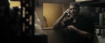Movie still from “RocknRolla” (2008), directed by Guy Ritchie – A man holding a cell phone in a bathroom; Medium shot, Low angle
