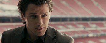 Movie still from “RocknRolla” (2008), directed by Guy Ritchie – A person wearing a suit and tie; Close Up shot, Over the shoulder angle