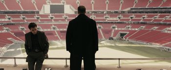 Movie still from “RocknRolla” (2008), directed by Guy Ritchie – A man standing in front of an empty stadium; Wide shot, High angle