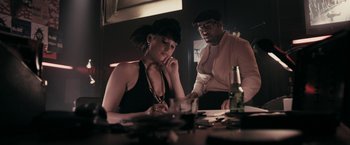 Movie still from “RocknRolla” (2008), directed by Guy Ritchie – A man and a woman sitting at a table with drinks; Medium shot, Low angle
