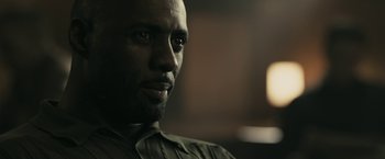 Movie still from “RocknRolla” (2008), directed by Guy Ritchie – A man's face in a dark room; Close Up shot, Over the shoulder angle