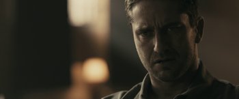 Movie still from “RocknRolla” (2008), directed by Guy Ritchie – A man's face in a dark room; Close Up shot, Over the shoulder angle