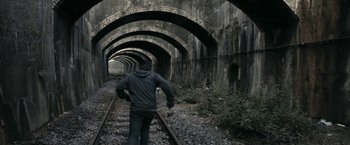 Movie still from “RocknRolla” (2008), directed by Guy Ritchie – A man is walking along the train tracks; Wide shot, High angle
