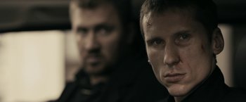 Movie still from “RocknRolla” (2008), directed by Guy Ritchie – Two men are looking at the camera in the dark; Close Up shot, Over the shoulder angle