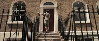 A woman is walking up the steps to a door