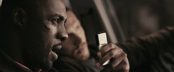 Movie still from “RocknRolla” (2008), directed by Guy Ritchie – Two men are looking at a cell phone; Close Up shot, Over the shoulder angle