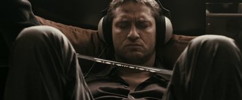 Movie still from “RocknRolla” (2008), directed by Guy Ritchie – A man with headphones is listening to music; Close Up shot, High angle