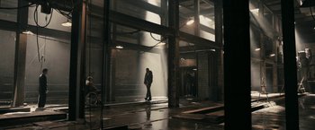 Movie still from “RocknRolla” (2008), directed by Guy Ritchie – A man standing in the middle of an indoor area; Wide shot, High angle