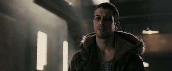 Movie still from “RocknRolla” (2008), directed by Guy Ritchie – A man in a brown jacket is looking at the camera; Close Up shot, Over the shoulder angle