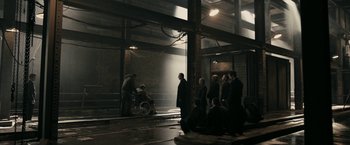 Movie still from “RocknRolla” (2008), directed by Guy Ritchie – A group of people standing around a building; Wide shot, High angle