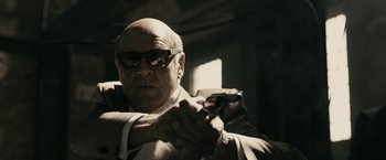 Movie still from “RocknRolla” (2008), directed by Guy Ritchie – An older man holding a cell phone in his hand; Close Up shot, Low angle