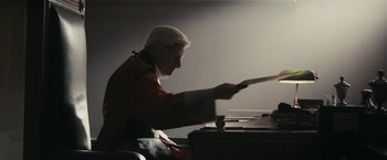 Movie still from “RocknRolla” (2008), directed by Guy Ritchie – An old man is playing the piano in a dark room; Medium shot, Low angle