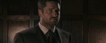 Movie still from “RocknRolla” (2008), directed by Guy Ritchie – A person wearing a suit and tie; Close Up shot, Low angle