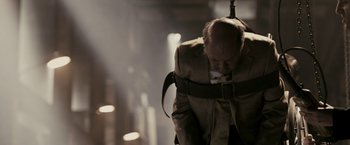 Movie still from “RocknRolla” (2008), directed by Guy Ritchie – An old man wearing a coat and a tie; Medium shot, Over the shoulder angle