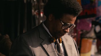 Movie still from “Roman J. Israel, Esq.” (2017), directed by Dan Gilroy – A man in a suit and tie with headphones on; Close Up shot, Over the shoulder angle