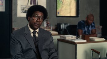 Movie still from “Roman J. Israel, Esq.” (2017), directed by Dan Gilroy – A man in a suit sitting in front of a television; Medium shot, Over the shoulder angle
