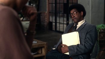 Movie still from “Roman J. Israel, Esq.” (2017), directed by Dan Gilroy – A man sitting in a chair holding papers; Medium shot, Over the shoulder angle