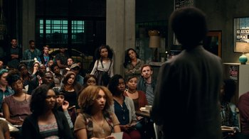 Movie still from “Roman J. Israel, Esq.” (2017), directed by Dan Gilroy – A group of people sitting in front of an audience; Wide shot, Over the shoulder angle