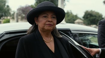 Movie still from “Roman J. Israel, Esq.” (2017), directed by Dan Gilroy – An older woman wearing a black hat and a black suit; Close Up shot, Over the shoulder angle