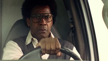 Movie still from “Roman J. Israel, Esq.” (2017), directed by Dan Gilroy – A man with glasses driving a car in the street; Close Up shot, Low angle