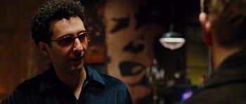 Movie still from “Rounders” (1998), directed by John Dahl – A man wearing glasses standing in front of a painting; Close Up shot, Over the shoulder angle