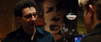 Movie still from “Rounders” (1998), directed by John Dahl – A man wearing glasses standing in front of a painting; Close Up shot, Over the shoulder angle