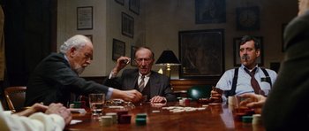 Movie still from “Rounders” (1998), directed by John Dahl – A group of men sitting at a table playing a game of dominoes; Wide shot, Over the shoulder angle