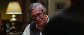 Movie still from “Rounders” (1998), directed by John Dahl – An older man wearing glasses and a sweater vest; Close Up shot, Over the shoulder angle