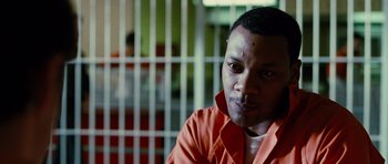 Movie still from “Rounders” (1998), directed by John Dahl – A man in an orange shirt in front of a jail cell; Close Up shot, Low angle