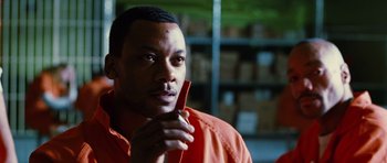 Movie still from “Rounders” (1998), directed by John Dahl – A man in an orange shirt is holding a cell phone; Close Up shot, Over the shoulder angle