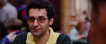 Movie still from “Rounders” (1998), directed by John Dahl – A person wearing glasses and smiling; Close Up shot, Over the shoulder angle
