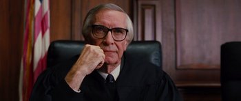 Movie still from “Rounders” (1998), directed by John Dahl – An older man in a judge's robe sitting in a chair; Close Up shot, Low angle