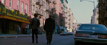Movie still from “Rounders” (1998), directed by John Dahl – Two people walking down the street in front of some buildings; Wide shot, Low angle
