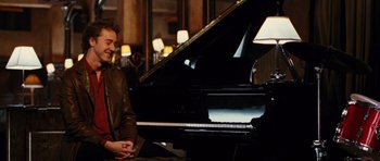 Movie still from “Rounders” (1998), directed by John Dahl – A man sitting in front of a black grand piano; Medium shot, Over the shoulder angle