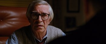 Movie still from “Rounders” (1998), directed by John Dahl – An older man wearing glasses looking at the camera; Close Up shot, Over the shoulder angle