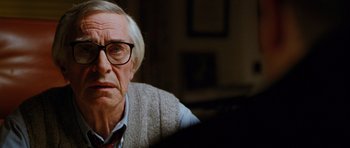 Movie still from “Rounders” (1998), directed by John Dahl – An older man wearing glasses looking at the camera; Close Up shot, Over the shoulder angle