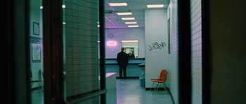Movie still from “Rounders” (1998), directed by John Dahl – A man standing in a room next to an orange chair; Wide shot, Over the shoulder angle