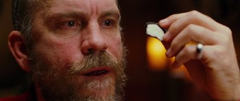 Movie still from “Rounders” (1998), directed by John Dahl – A person with a beard holding an object; Extreme Close Up shot, Over the shoulder angle