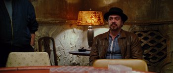 Movie still from “Rounders” (1998), directed by John Dahl – A man sitting at a table in front of a lamp; Medium shot, Over the shoulder angle