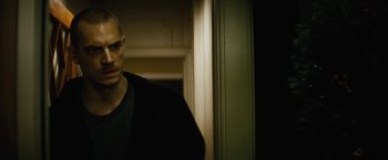 Movie still from “Run All Night” (2015), directed by Jaume Collet-Serra – A man standing in front of a door in a dark room; Close Up shot, Low angle