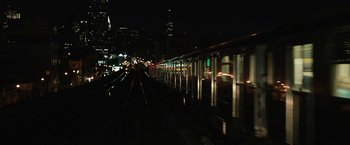 Movie still from “Run All Night” (2015), directed by Jaume Collet-Serra – A view of a train tracks at night with a city skyline in the background; Extreme Wide shot, High angle