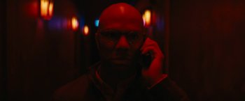 Movie still from “Run All Night” (2015), directed by Jaume Collet-Serra – A bald man with glasses is talking on a cell phone; Close Up shot, Low angle