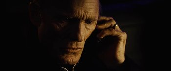 Movie still from “Run All Night” (2015), directed by Jaume Collet-Serra – An older man is looking at the camera while holding his hand to his ear; Close Up shot, Low angle