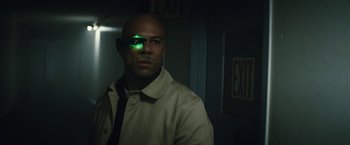 Movie still from “Run All Night” (2015), directed by Jaume Collet-Serra – A man with a green light on his eye; Close Up shot, Over the shoulder angle