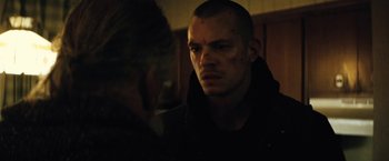 Movie still from “Run All Night” (2015), directed by Jaume Collet-Serra – A man in a dark room looking at another man in a dark room; Close Up shot, Over the shoulder angle